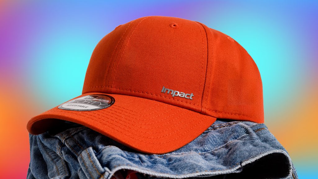 red branded cap on a folded pair of jeans and rainbow background.